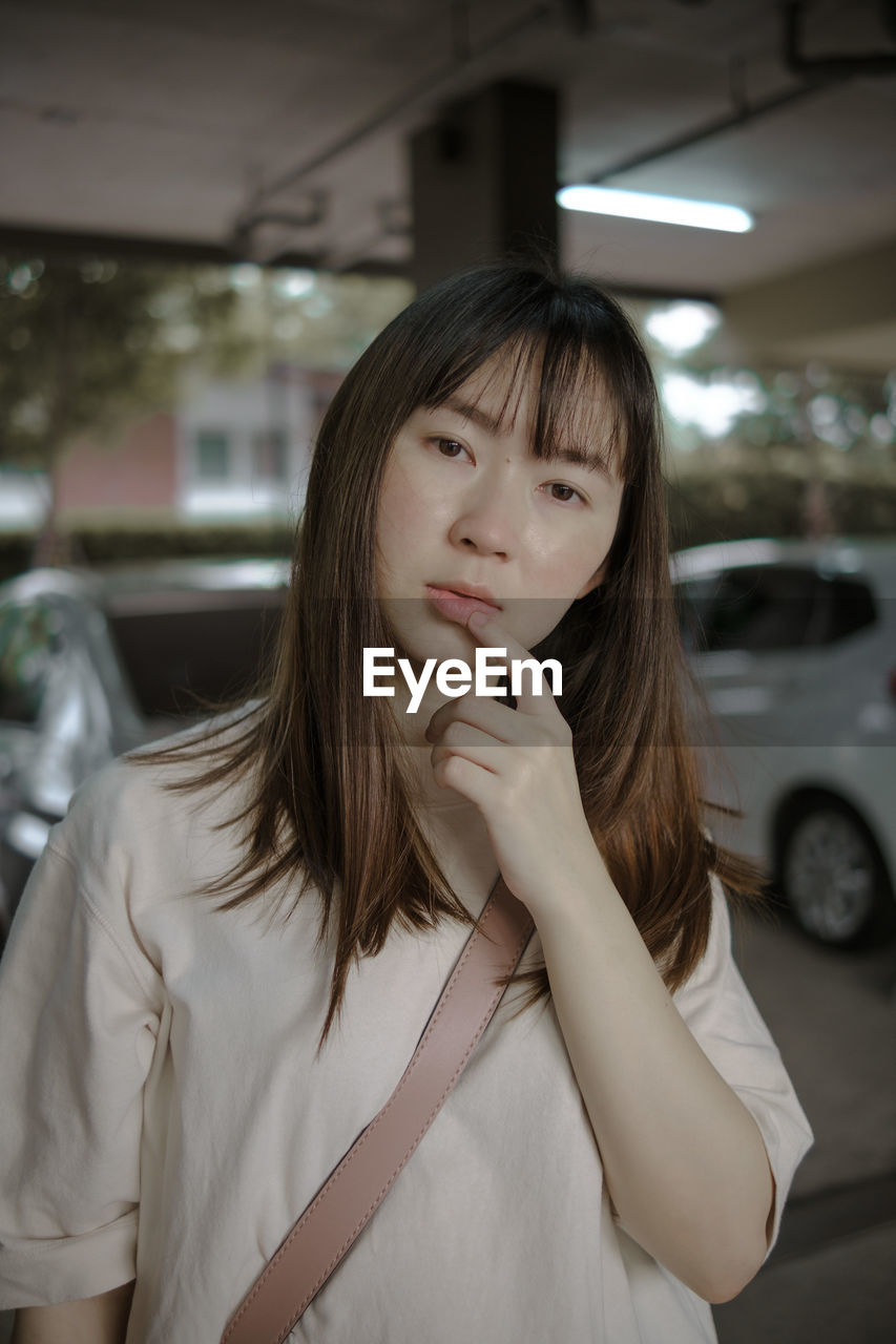 PORTRAIT OF TEENAGE GIRL HOLDING CAMERA AT CAR