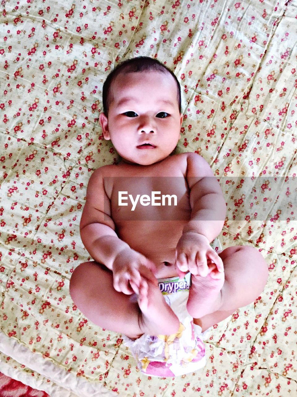 Portrait of cute baby girl lying on bed