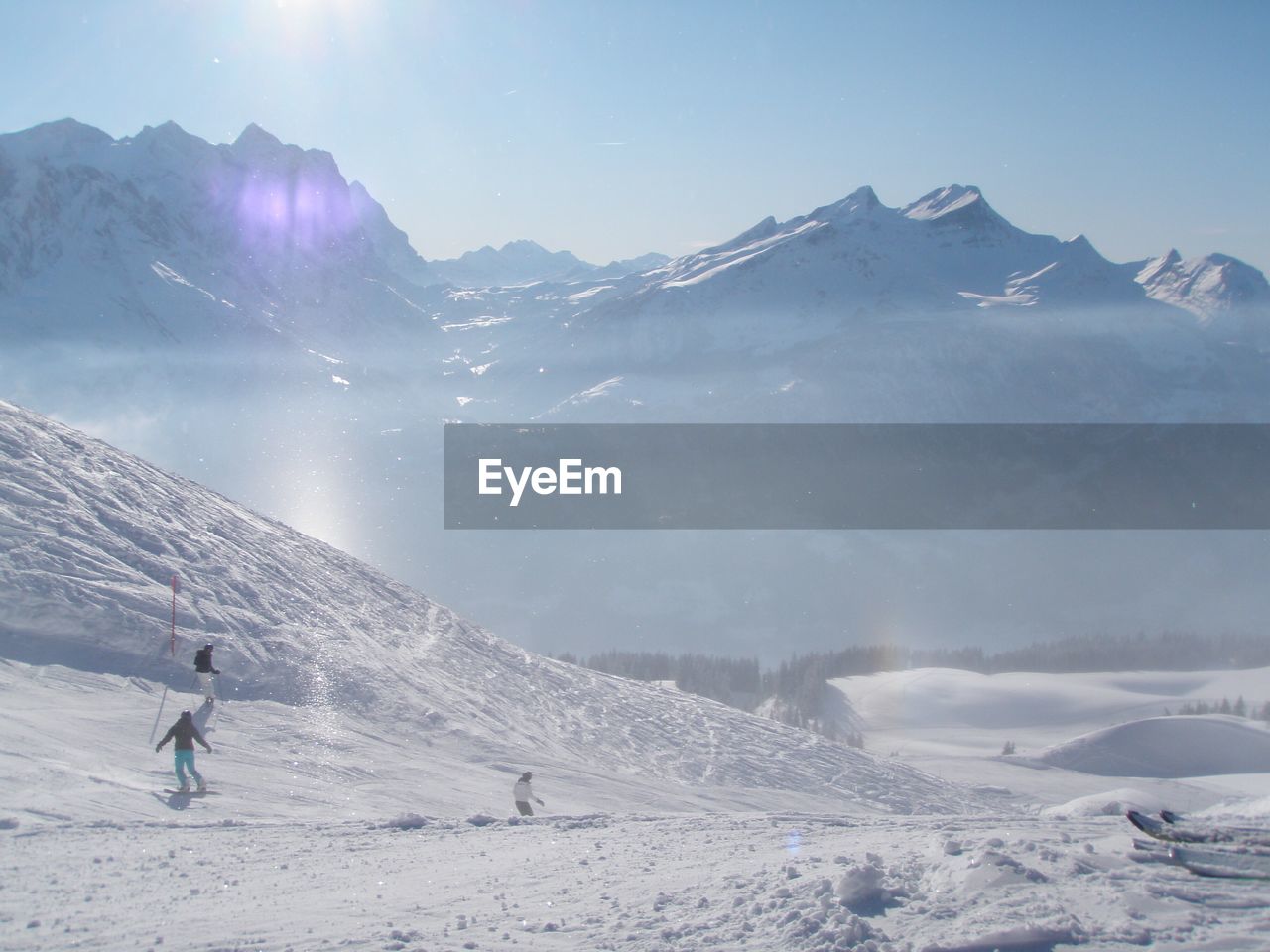 Scenic view of snowboarders in snow covered mountains