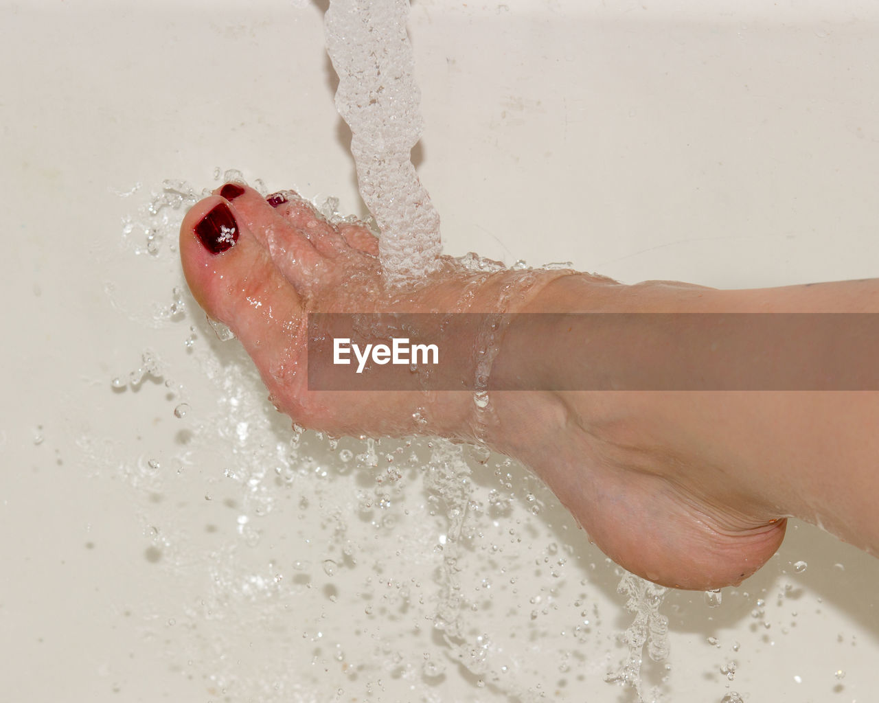 Low section of woman washing leg at home