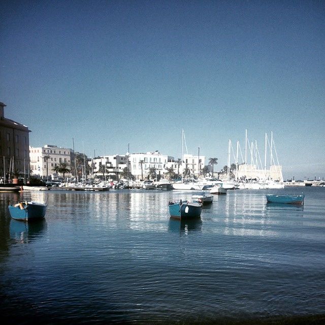 BOATS IN HARBOR WITH CITYSCAPE IN BACKGROUND