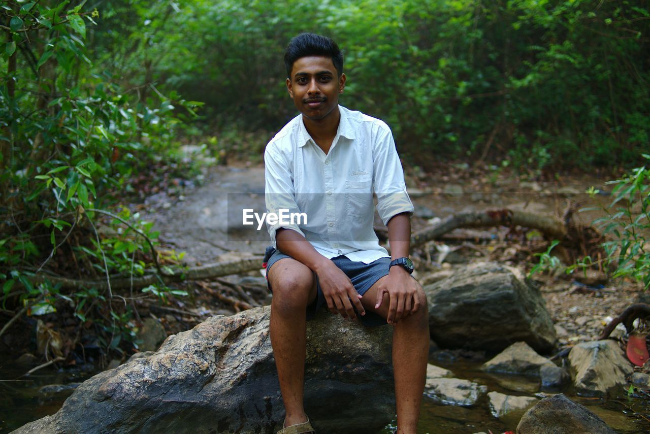 Portrait of young man sitting in forest