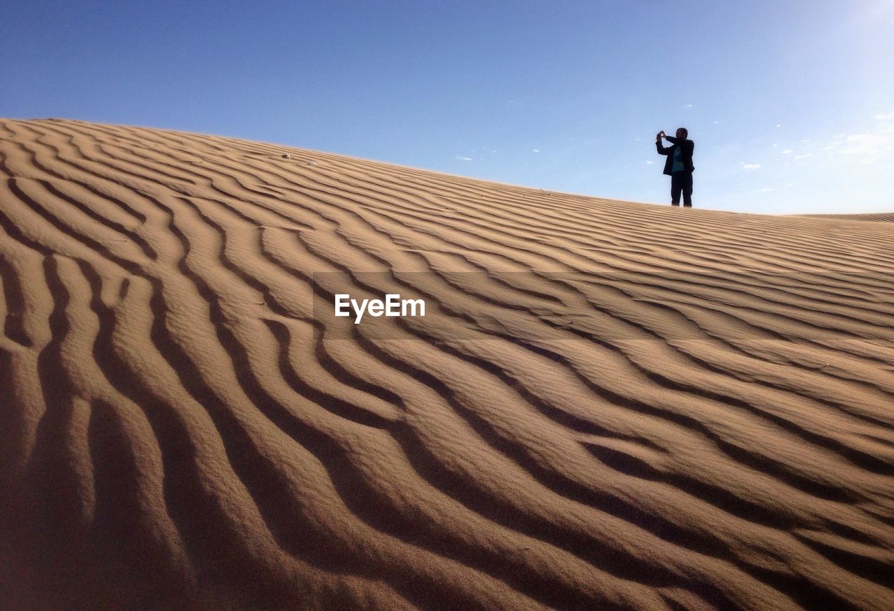 Man photographing in desert against sky