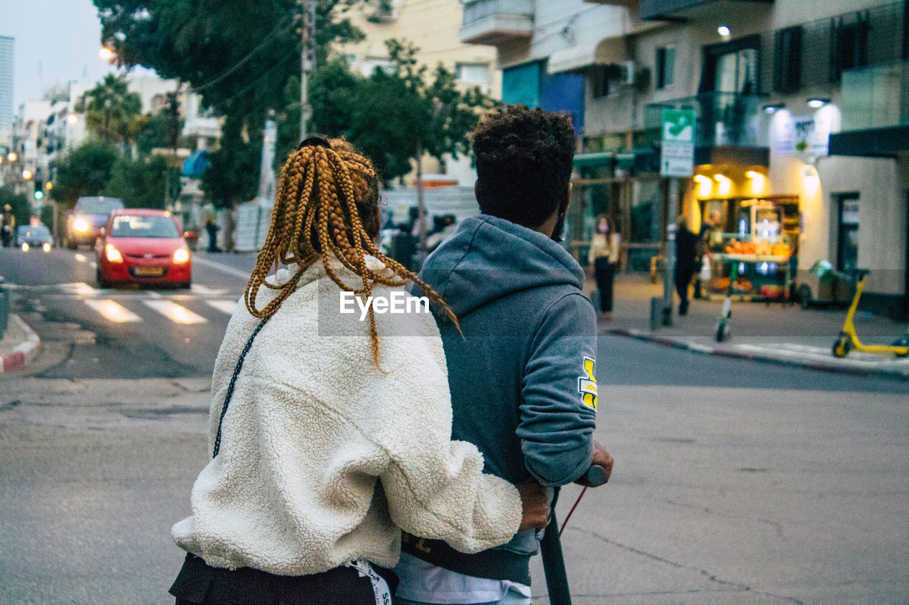 REAR VIEW OF WOMEN WALKING ON ROAD