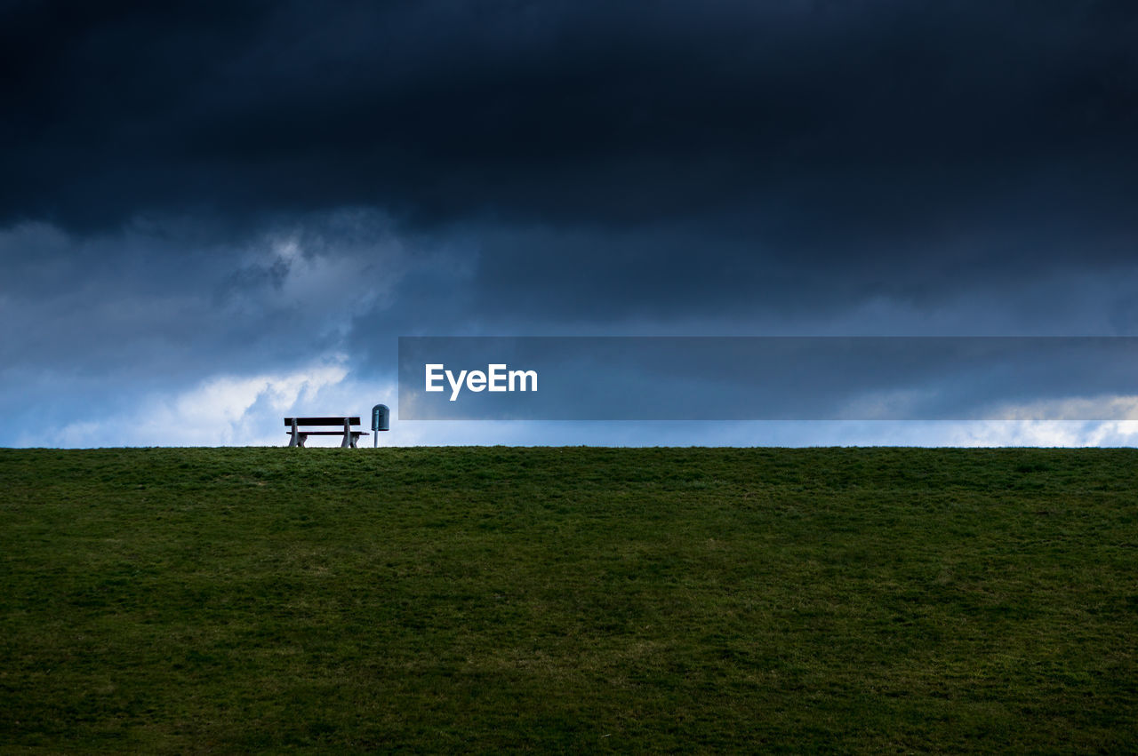 Scenic view of grassy field against cloudy sky