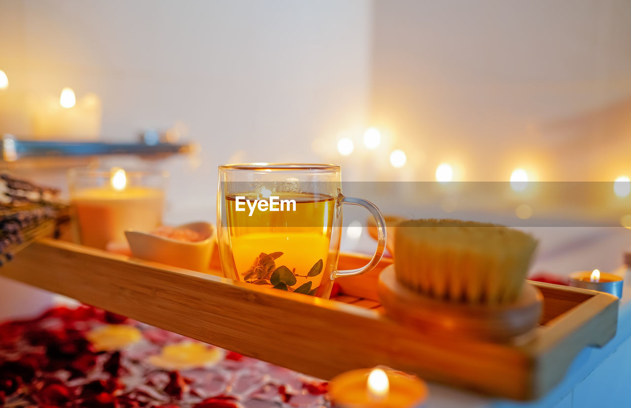 Herbal mint tea on bathtub tray with candles, lavender and salt during spiritual aura cleansing bath