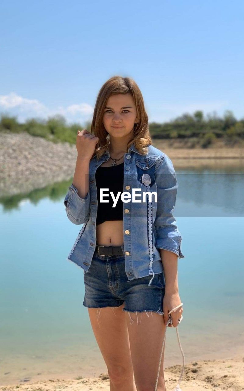 Portrait of teenage girl standing against sky