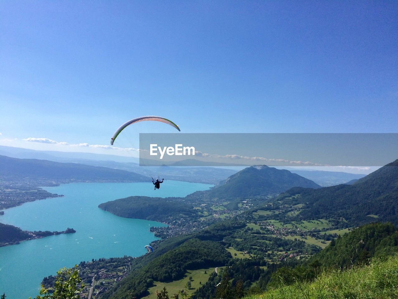 PERSON PARAGLIDING OVER MOUNTAIN AGAINST CLEAR SKY