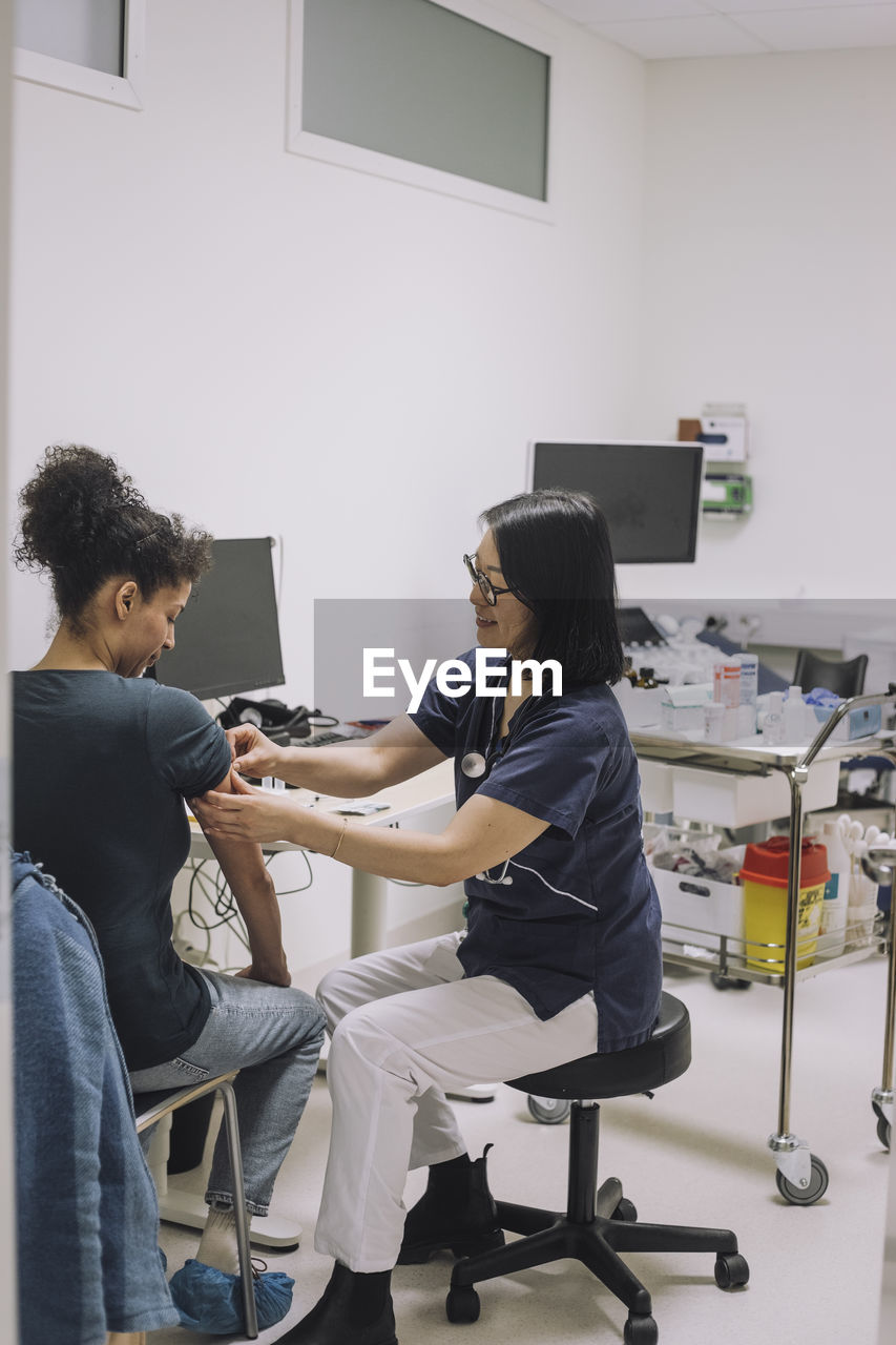 Full length of smiling female doctor examining patient in medical clinic