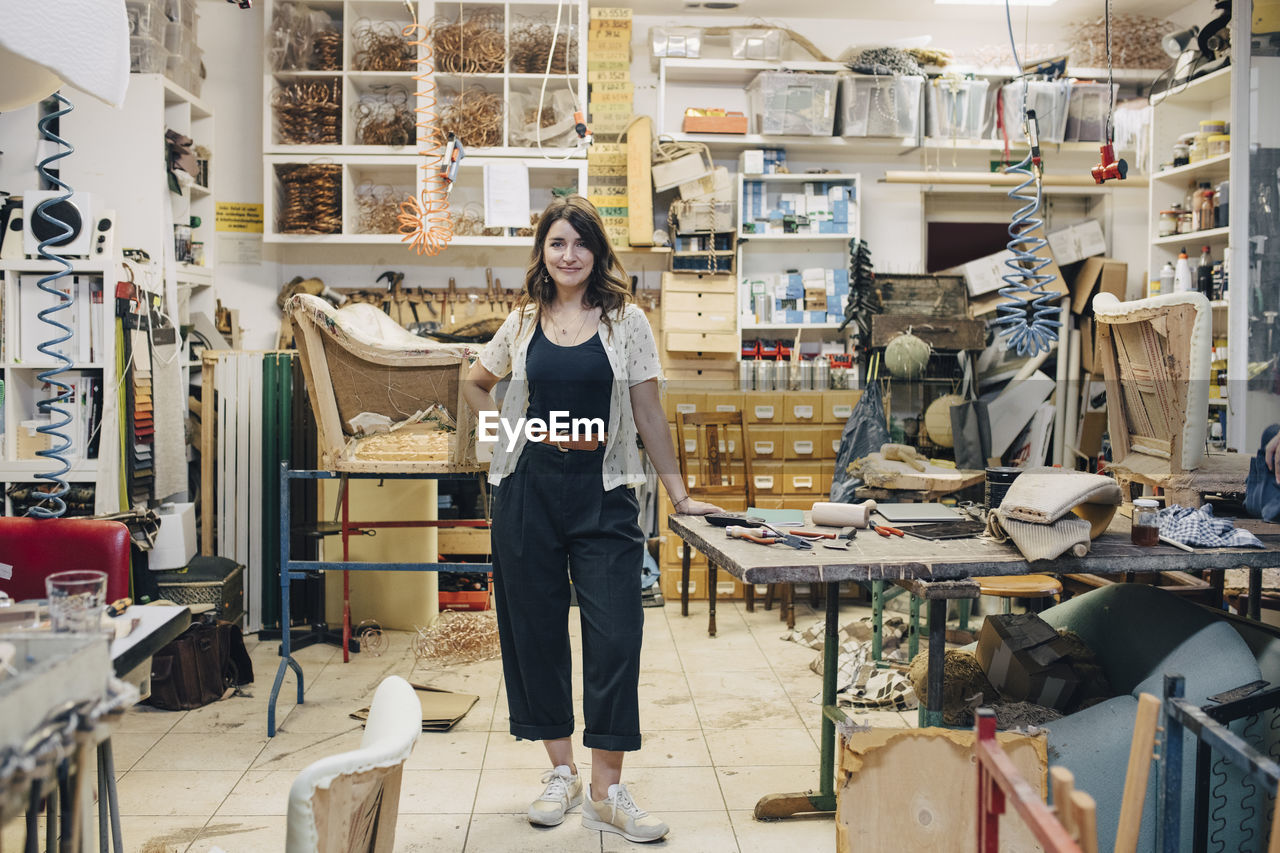 Portrait of confident female upholstery worker standing in workshop