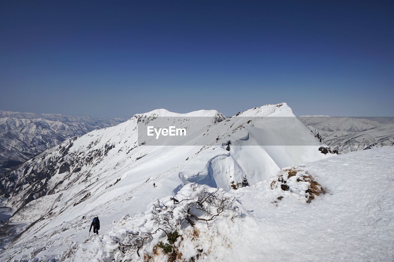 Scenic view of snowcapped mountains against clear blue sky