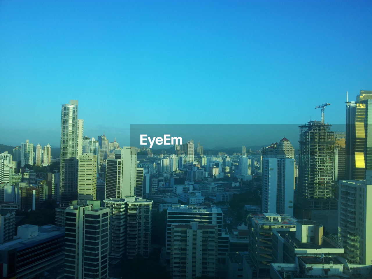 Illuminated cityscape against blue sky