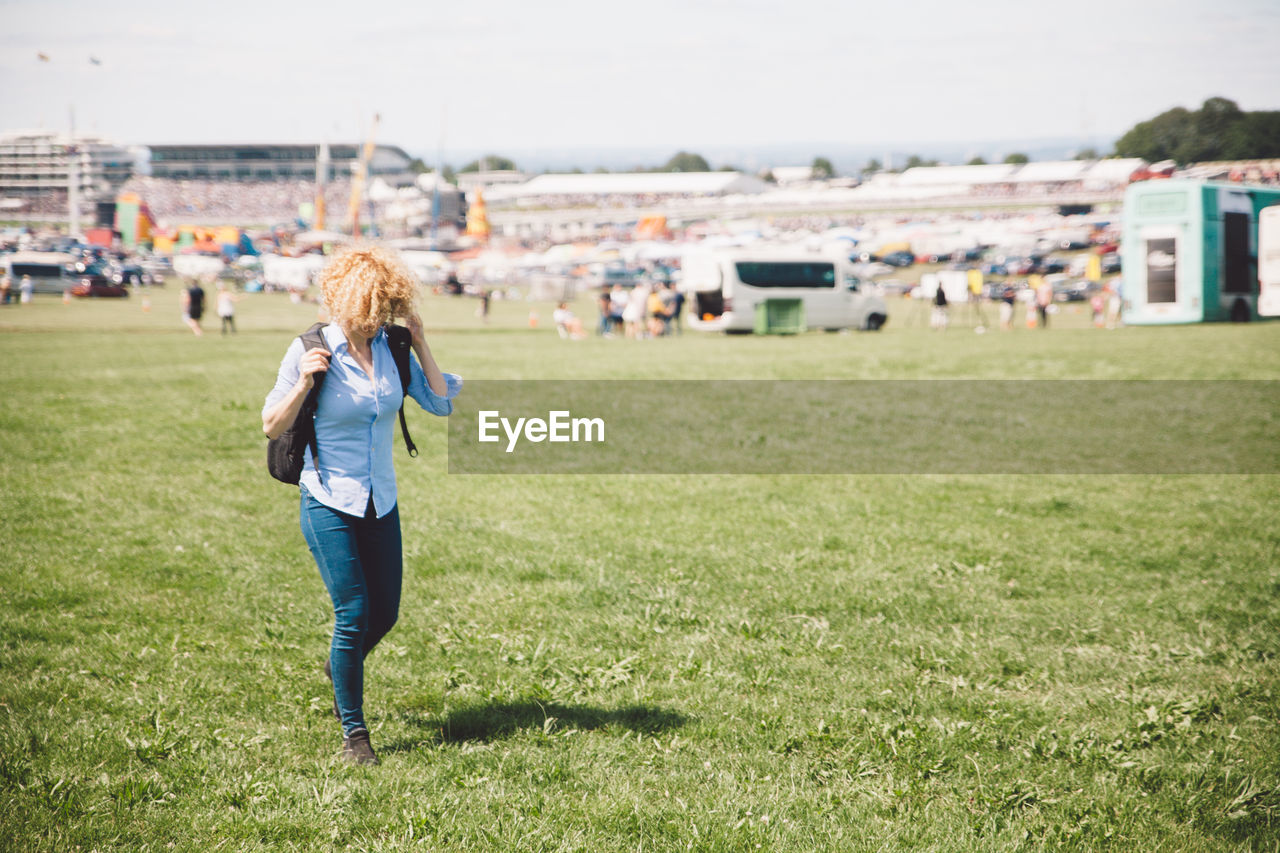 Woman walking on grassy field during sunny day