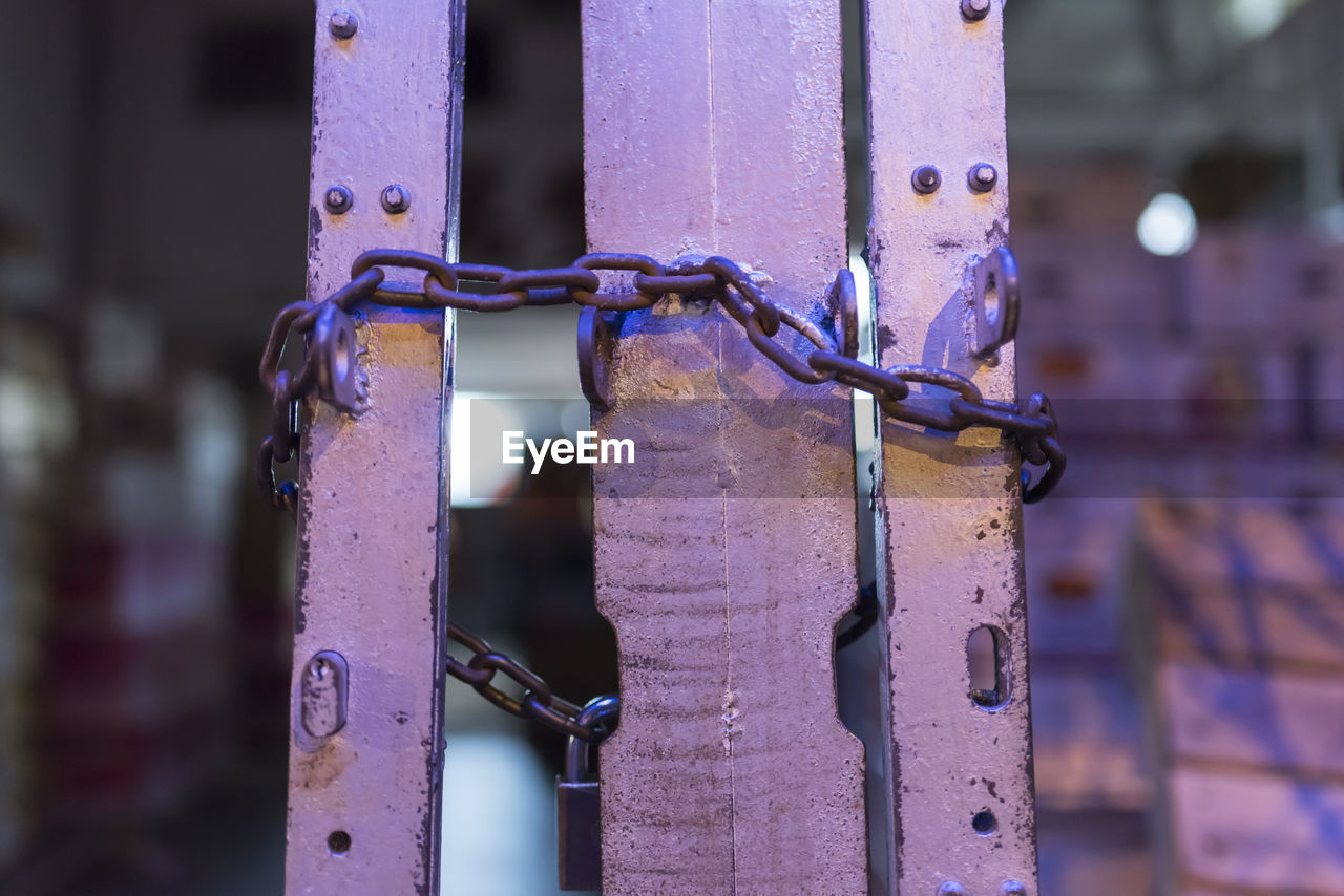 CLOSE-UP OF RUSTY METAL CHAIN ON FENCE