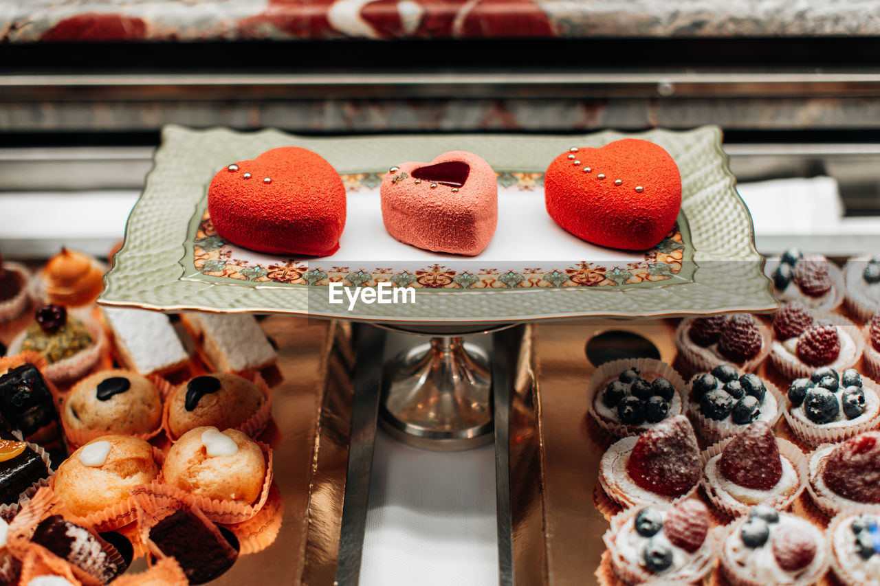 Cookies, sweet cakes with fluffy cream and red berries in form of hearts