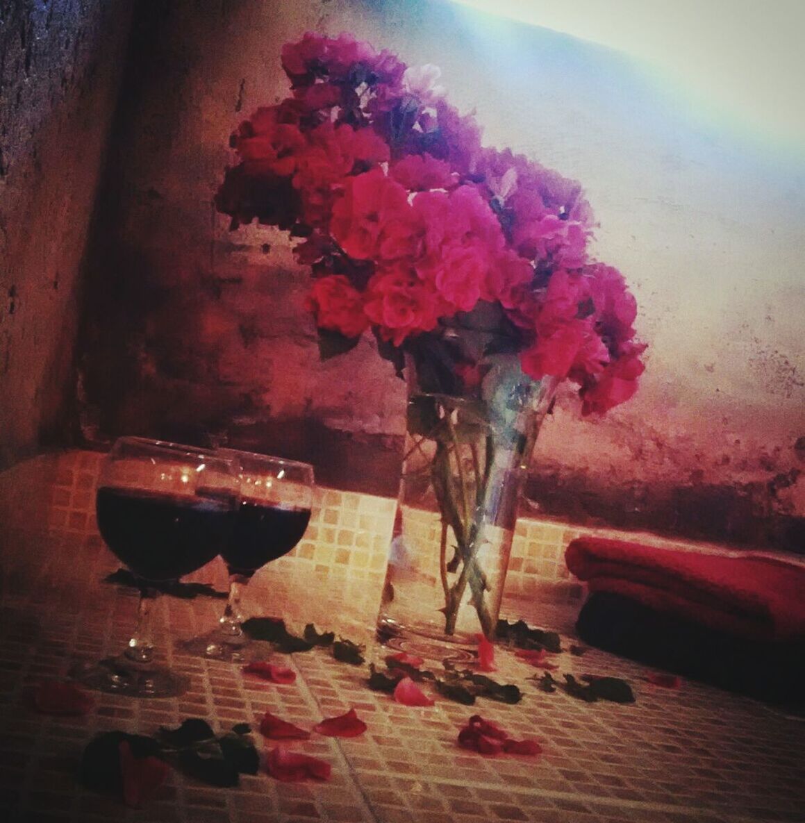 Red roses in vase by wine glasses