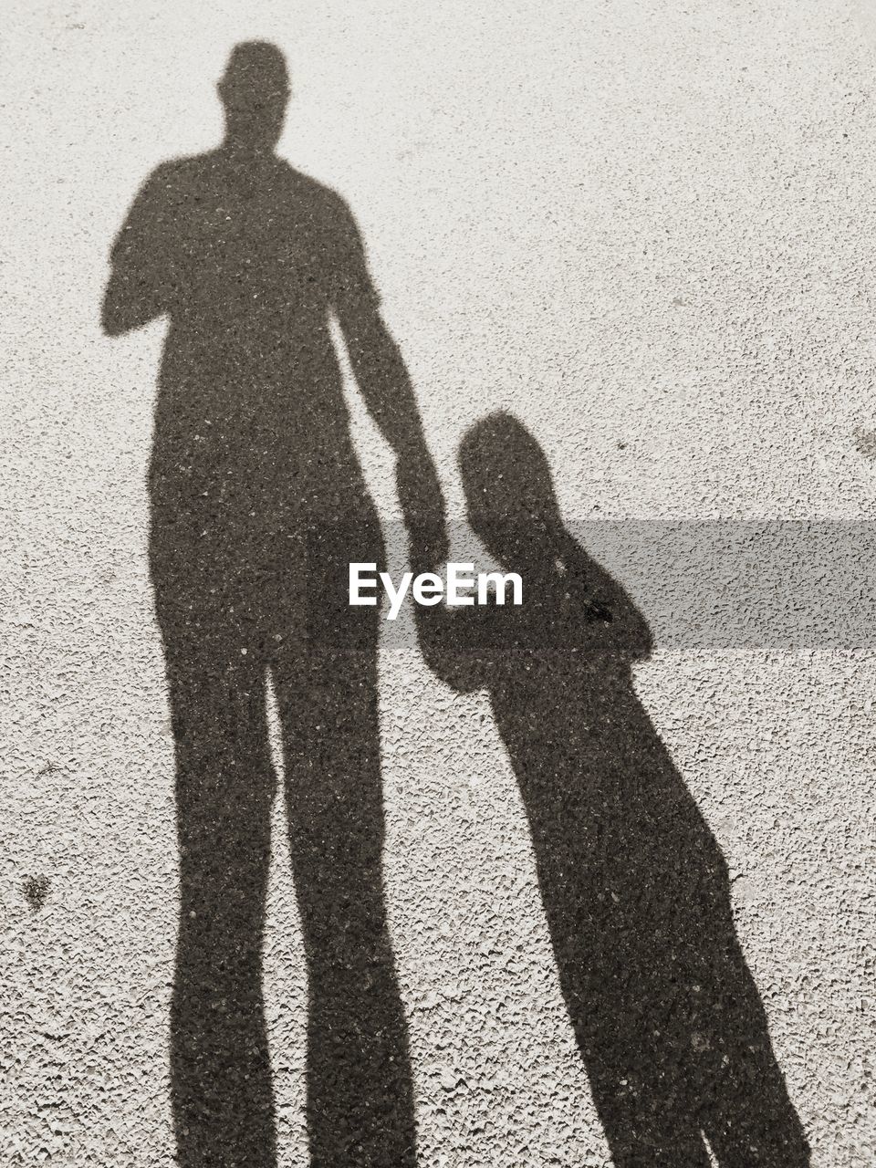 Shadow of father and son on road