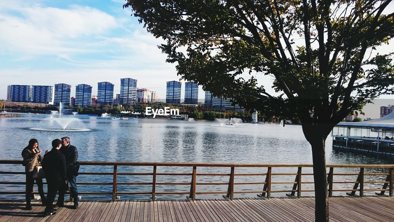 WOMAN STANDING ON BRIDGE OVER RIVER IN CITY