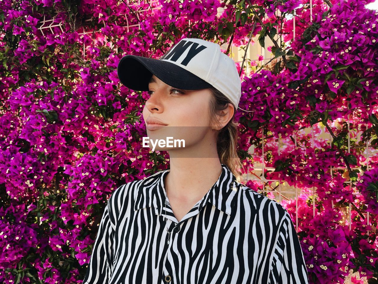 Portrait of young woman standing against plants