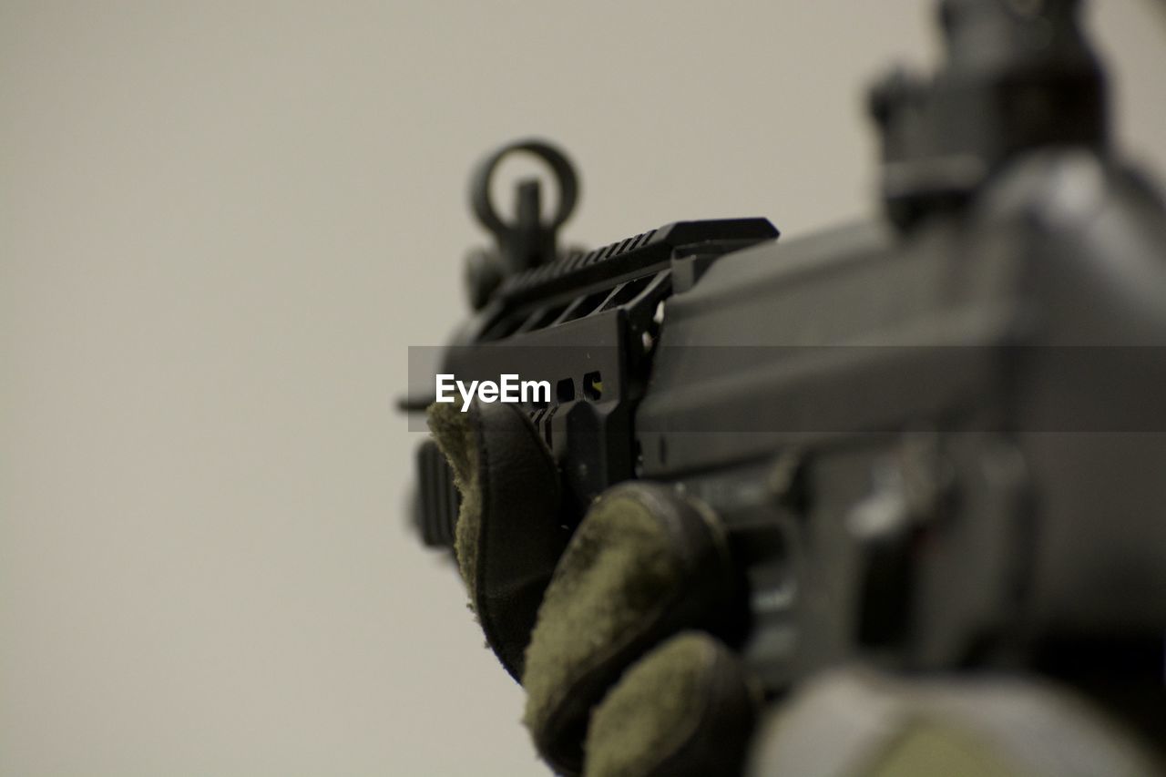 Close-up of hand holding gun over white background