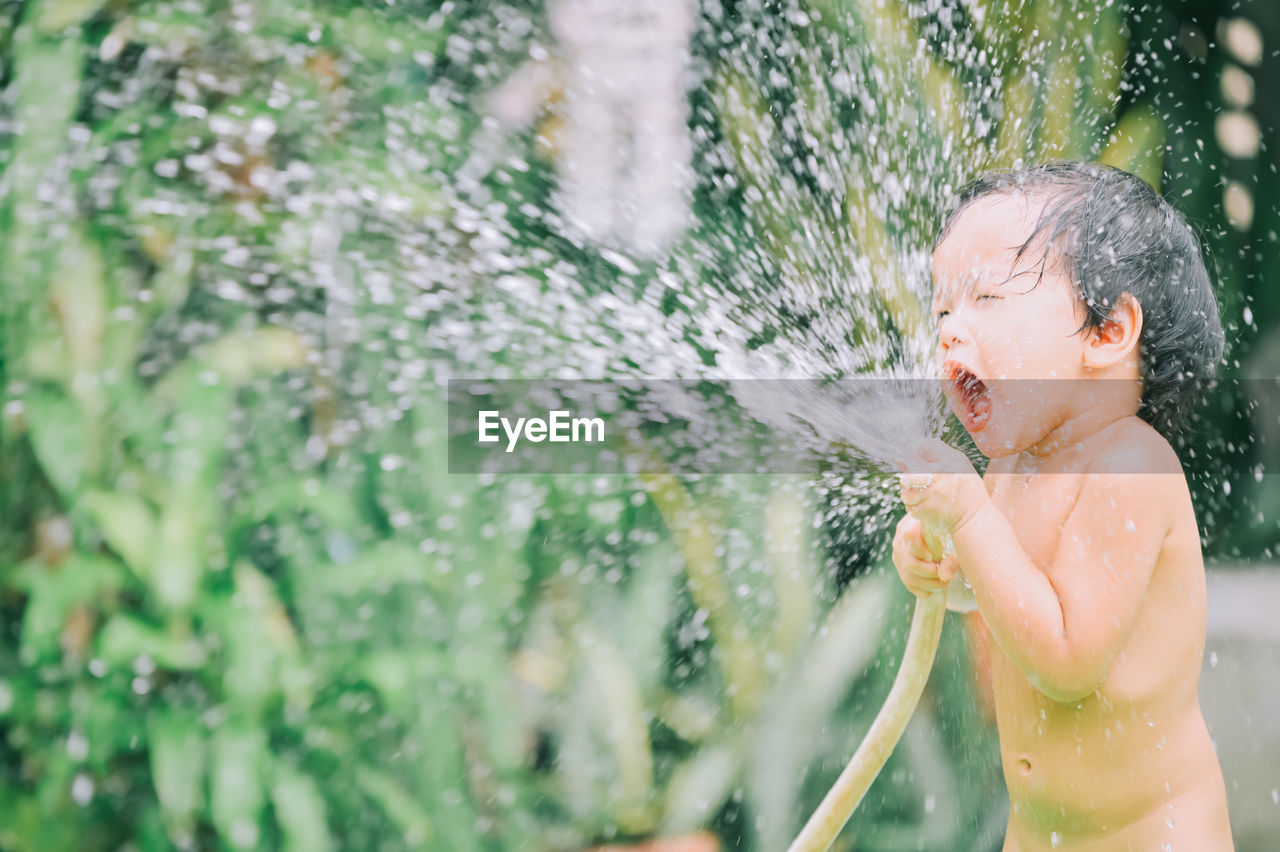 Cute girl playing with water pipe outdoors