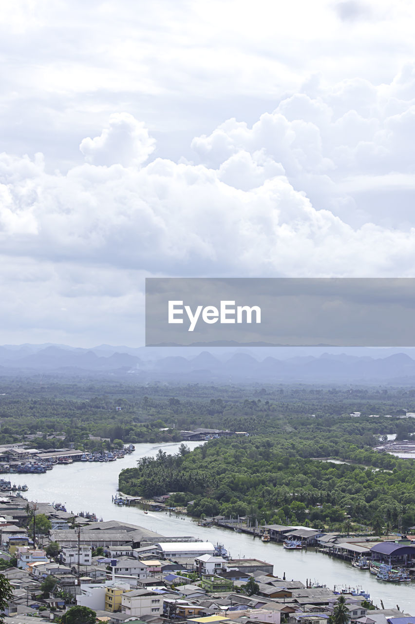 HIGH ANGLE VIEW OF TOWNSCAPE BY RIVER AGAINST SKY