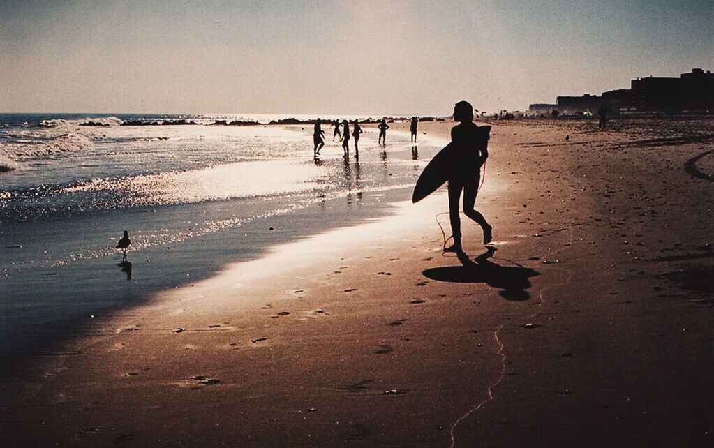 Silhouette surfer walking on beach
