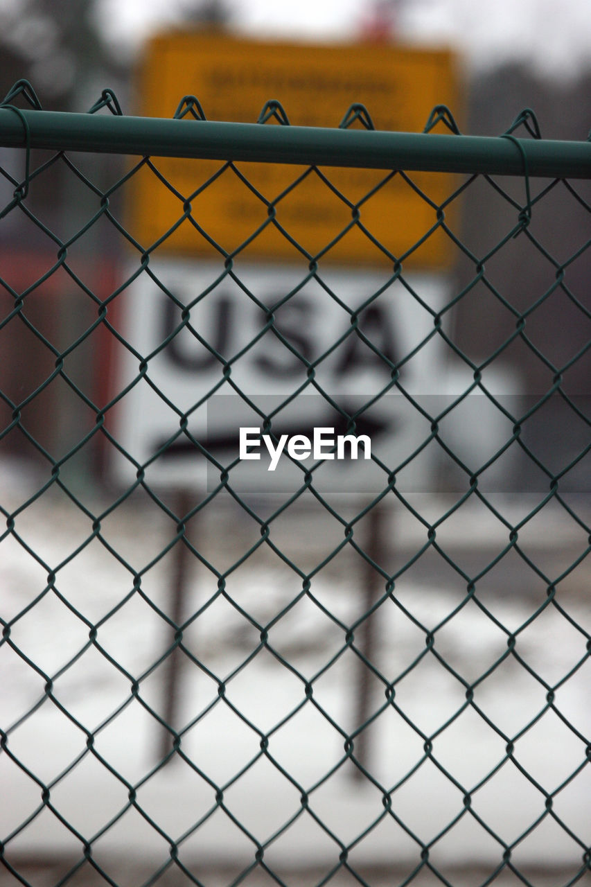 Close-up of chainlink fence against sign board