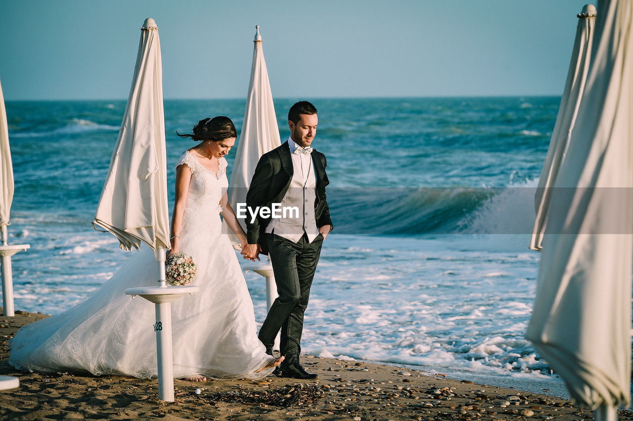 Bride and bridegroom walking on shore at beach