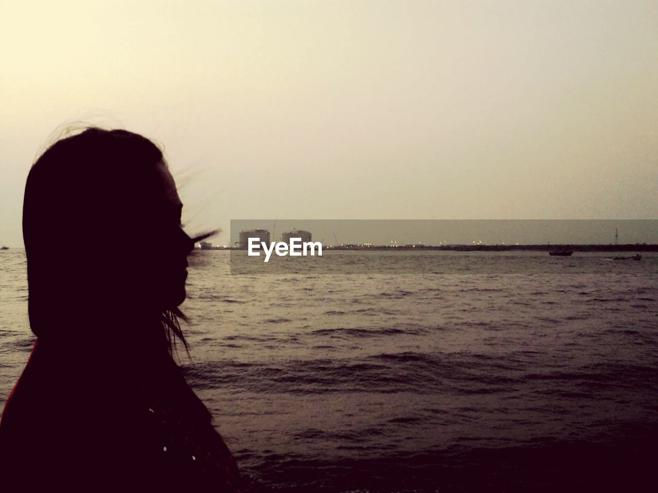 Silhouette woman against river and clear sky at dusk