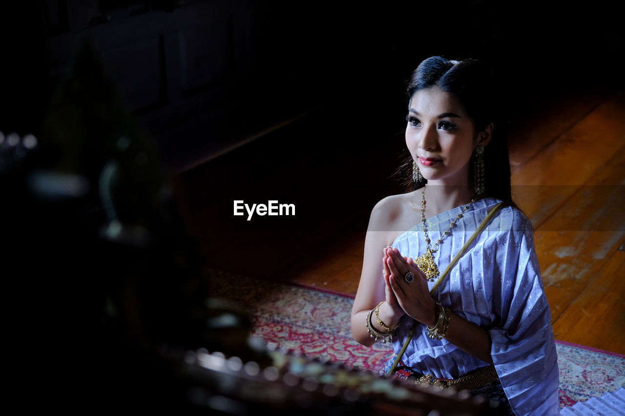 Beautiful young woman with hands clasped praying in temple