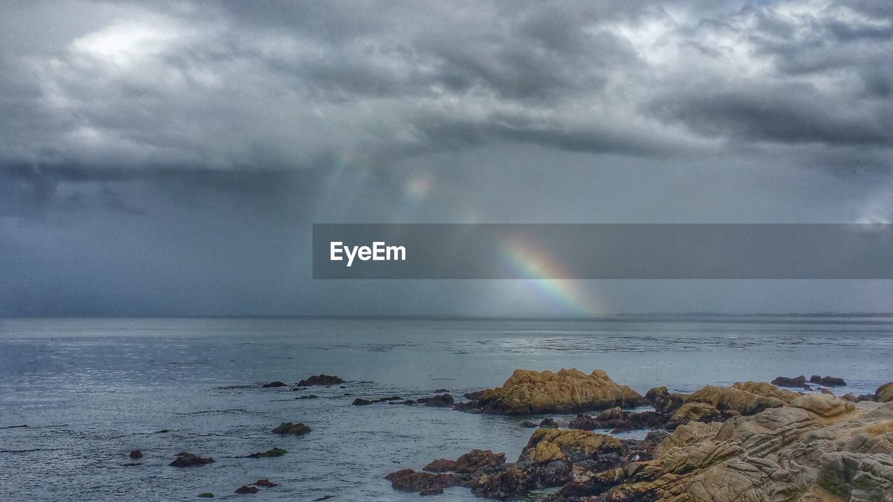 Scenic view of sea against rainbow cloudy sky