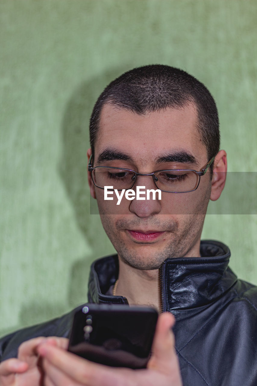 CLOSE-UP PORTRAIT OF YOUNG MAN USING PHONE