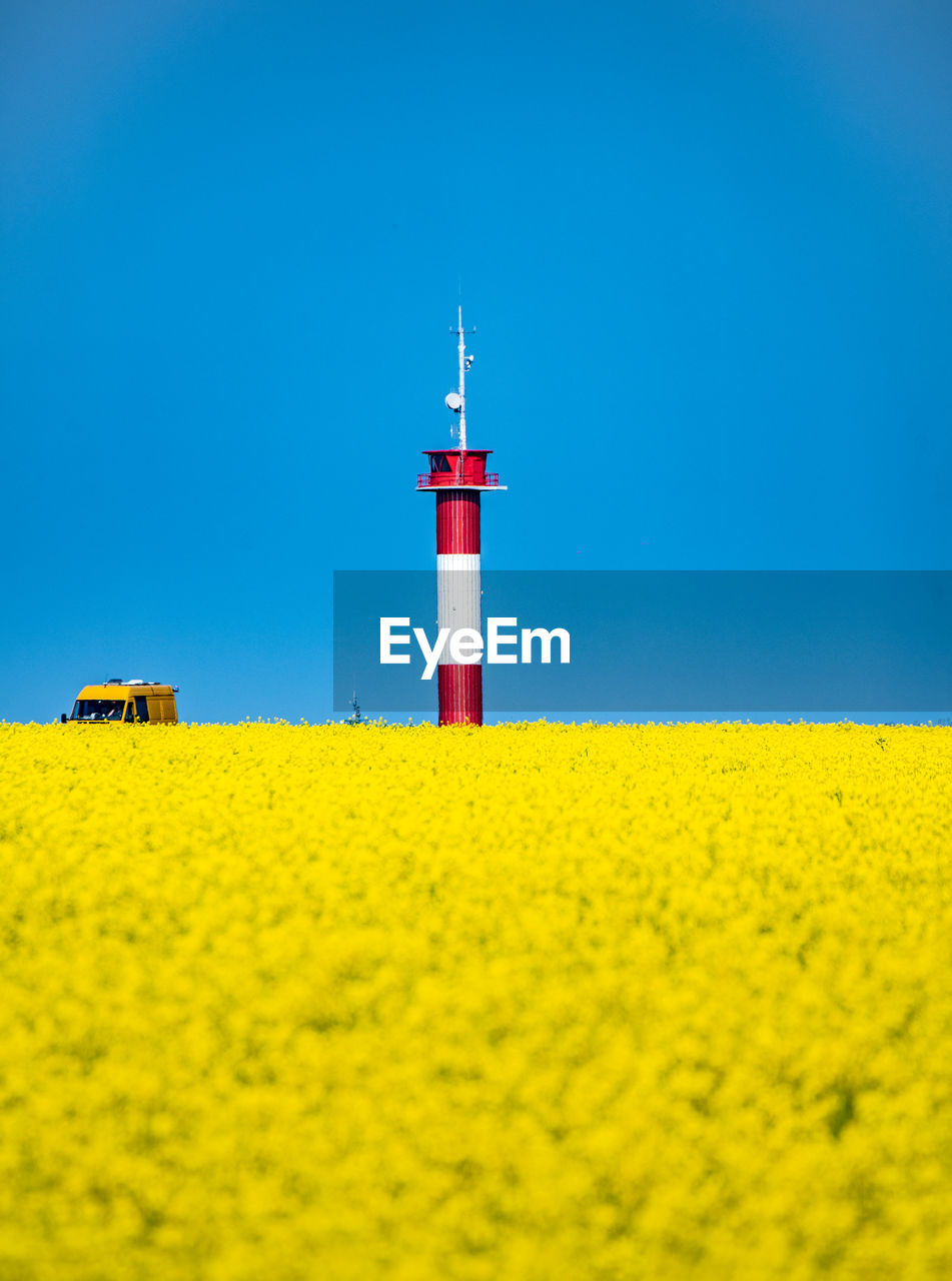 LIGHTHOUSE ON FIELD AGAINST CLEAR BLUE SKY