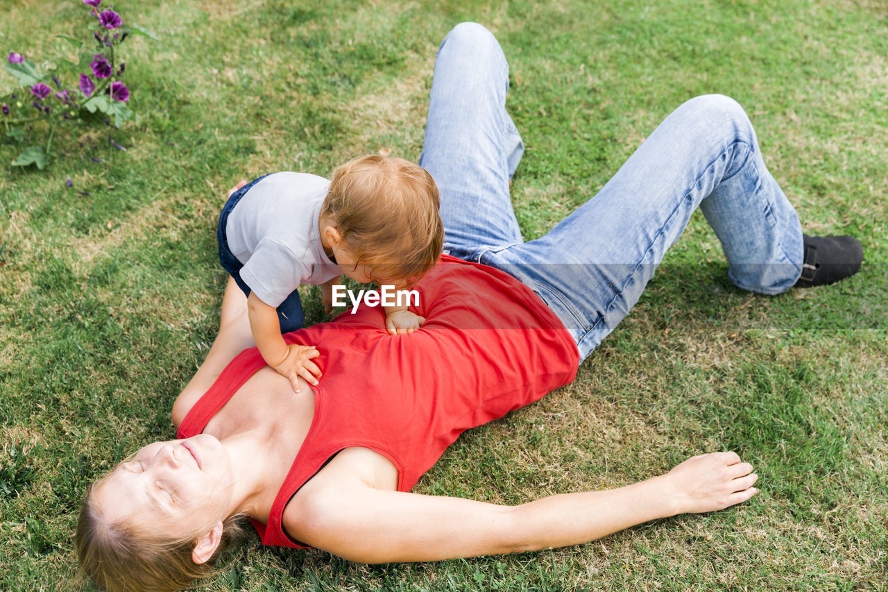 High angle view of mother with daughter lying on field at home