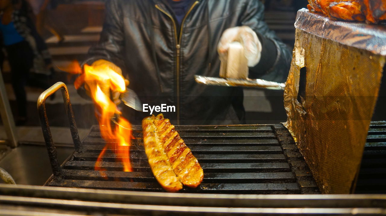 Midsection of person grilling meat on barbecue grill