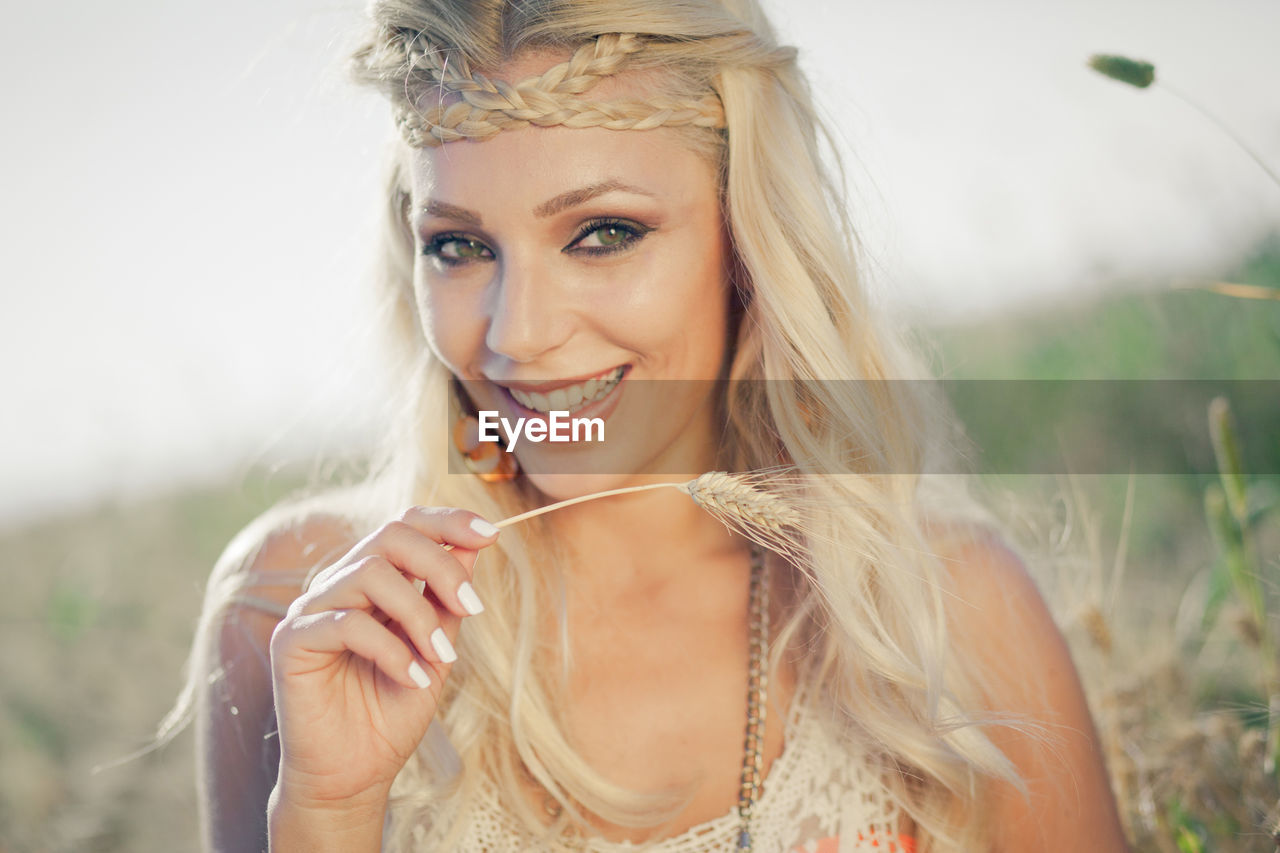 Portrait of beautiful woman with braided hair holding crop on field