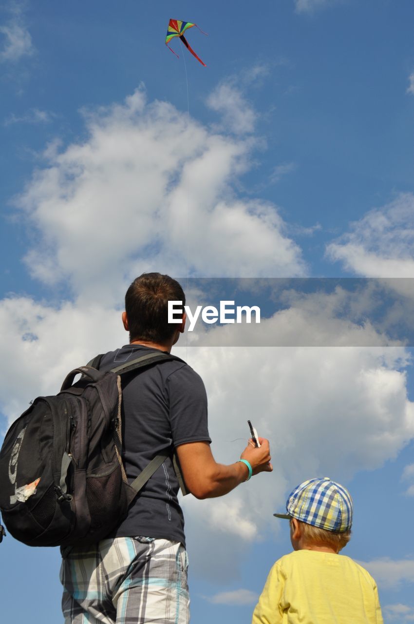 LOW ANGLE VIEW OF BOY STANDING AGAINST SKY