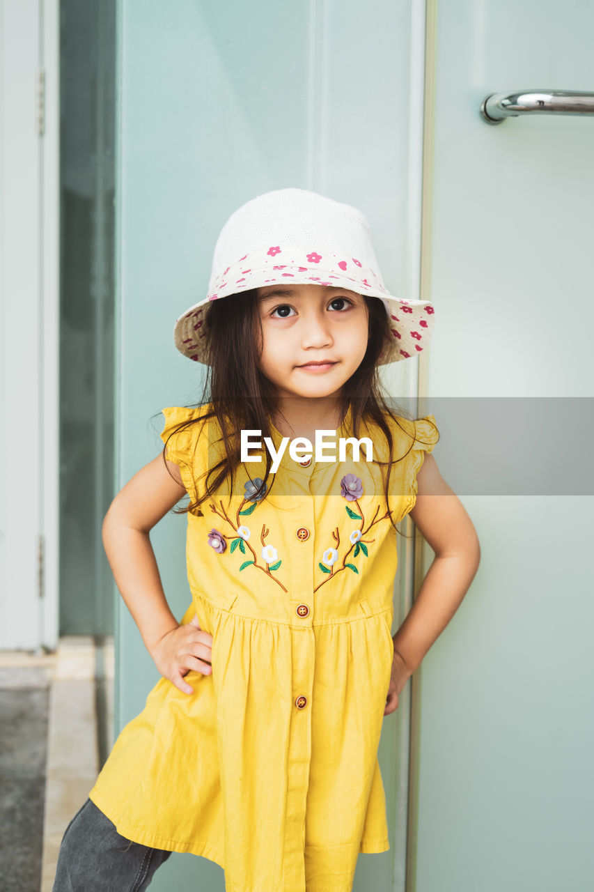 Portrait of beautiful little gorgeus lovely toddler girl in mustard summer look fashion dress, hat.