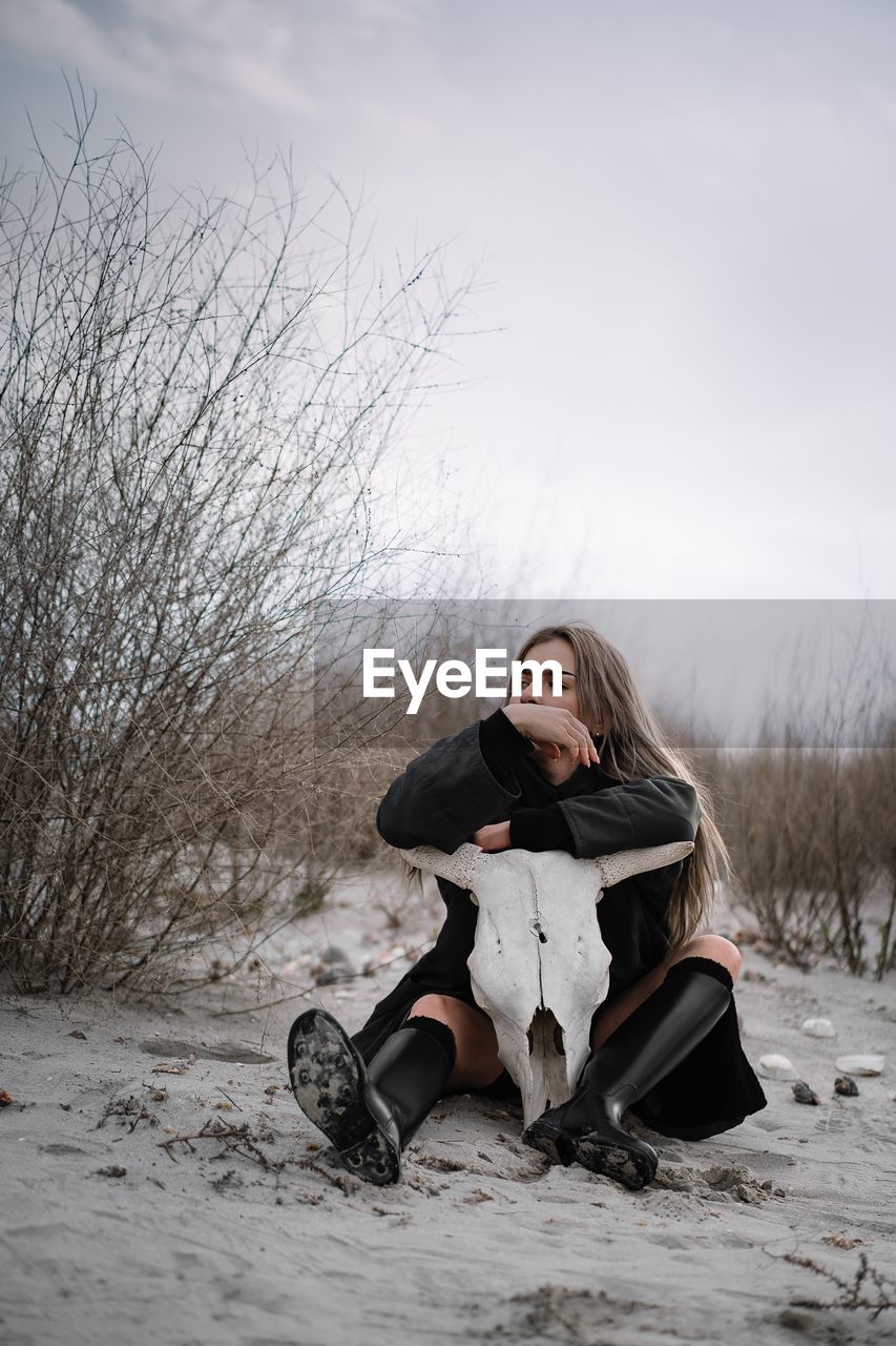 Woman sitting on sand on the beach in winter