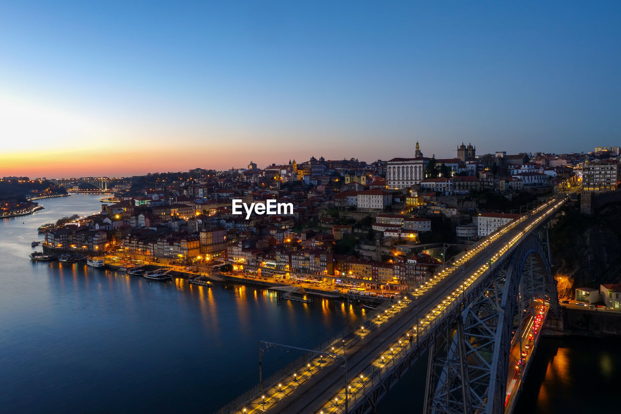 High angle view of illuminated city by river against sky