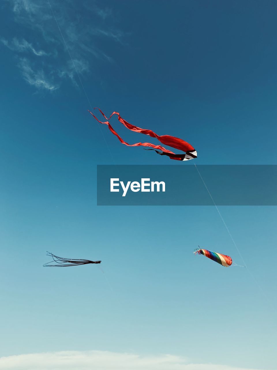 Low angle view of kites flying against blue sky