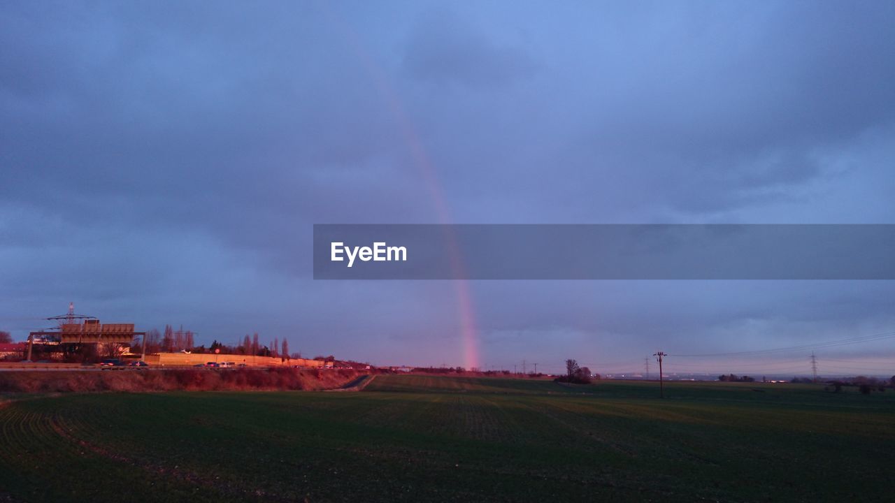 RAINBOW OVER FIELD AGAINST SKY