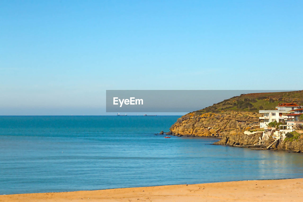 Scenic view of beach against clear blue sky on sunny day