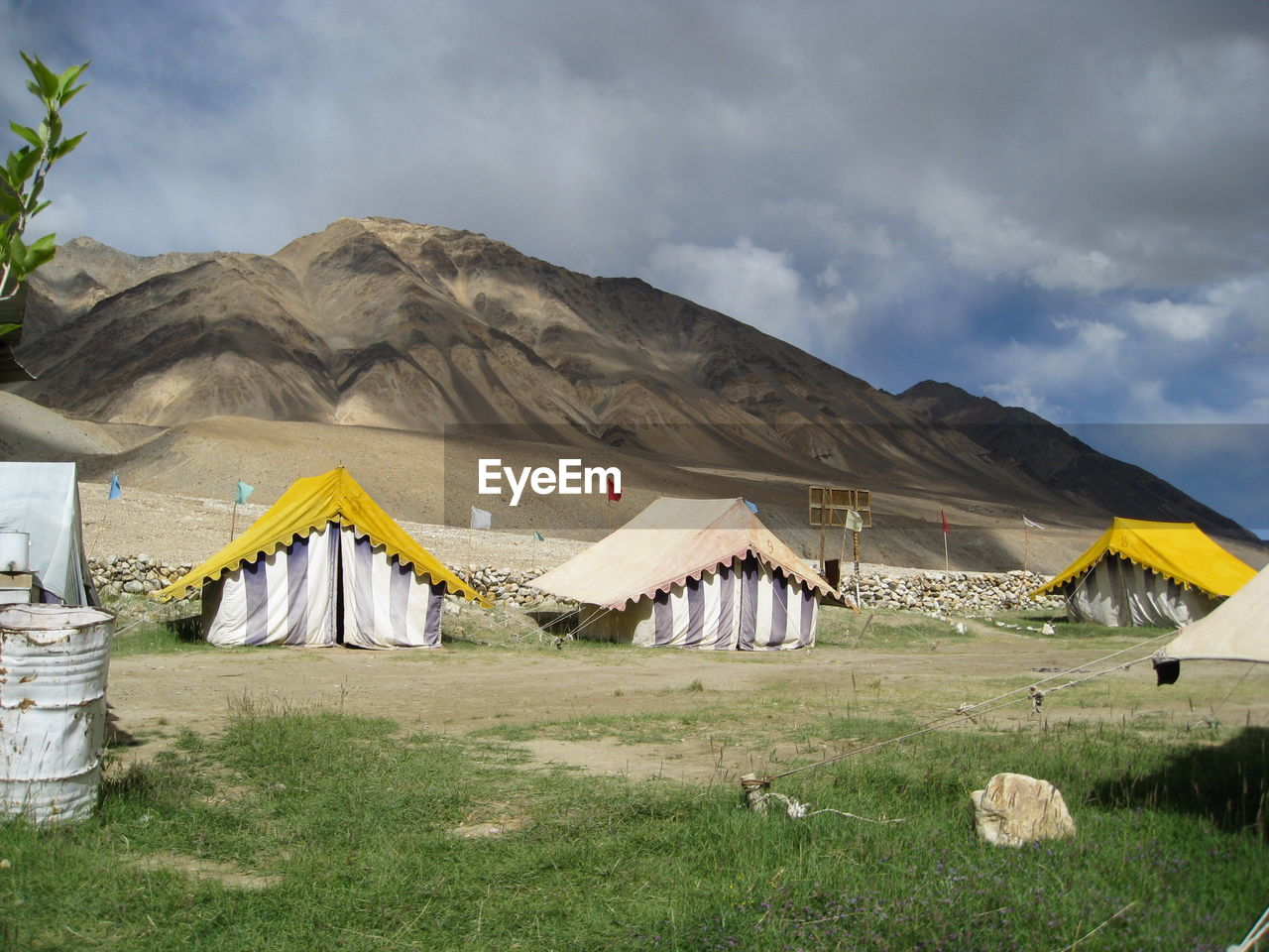 Tents at desert against cloudy sky