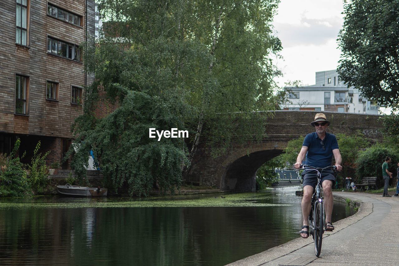 MAN RIDING BICYCLE ON CANAL