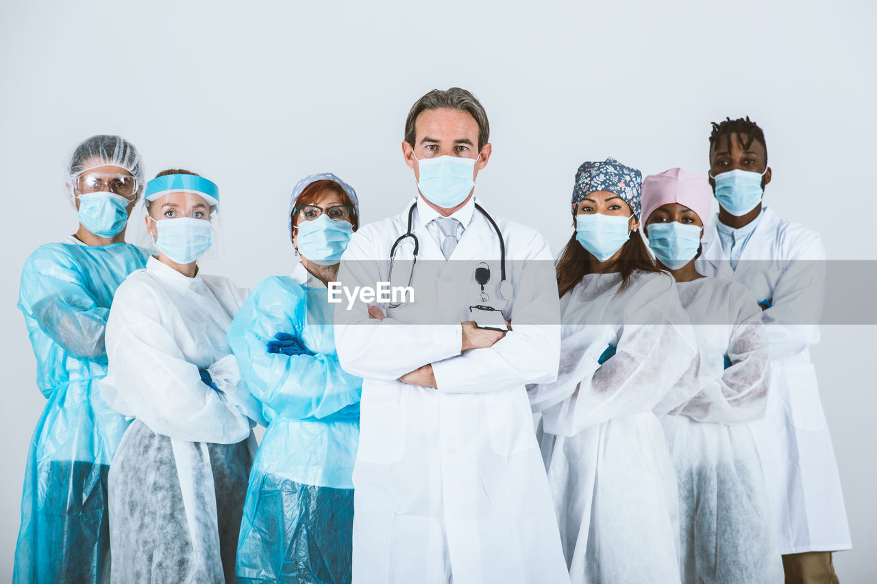 Portrait of doctors wearing mask standing against white background