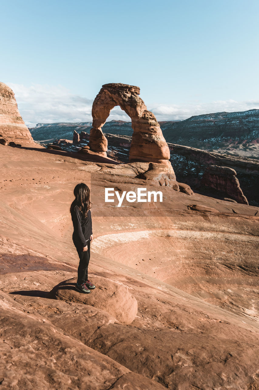 High angle view of woman standing on rock formation against sky