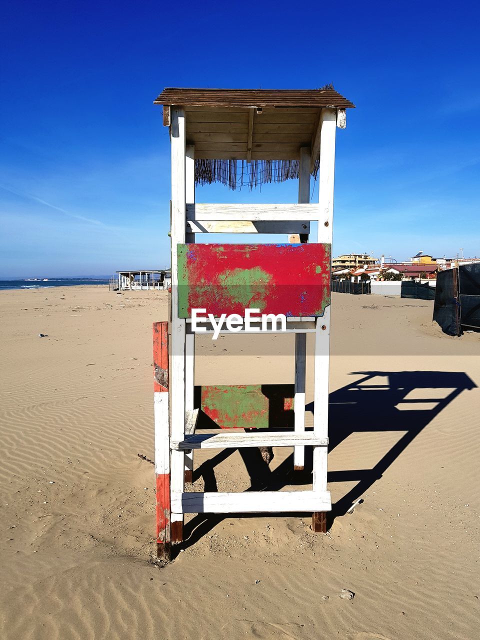 Lifeguard hut on beach against blue sky