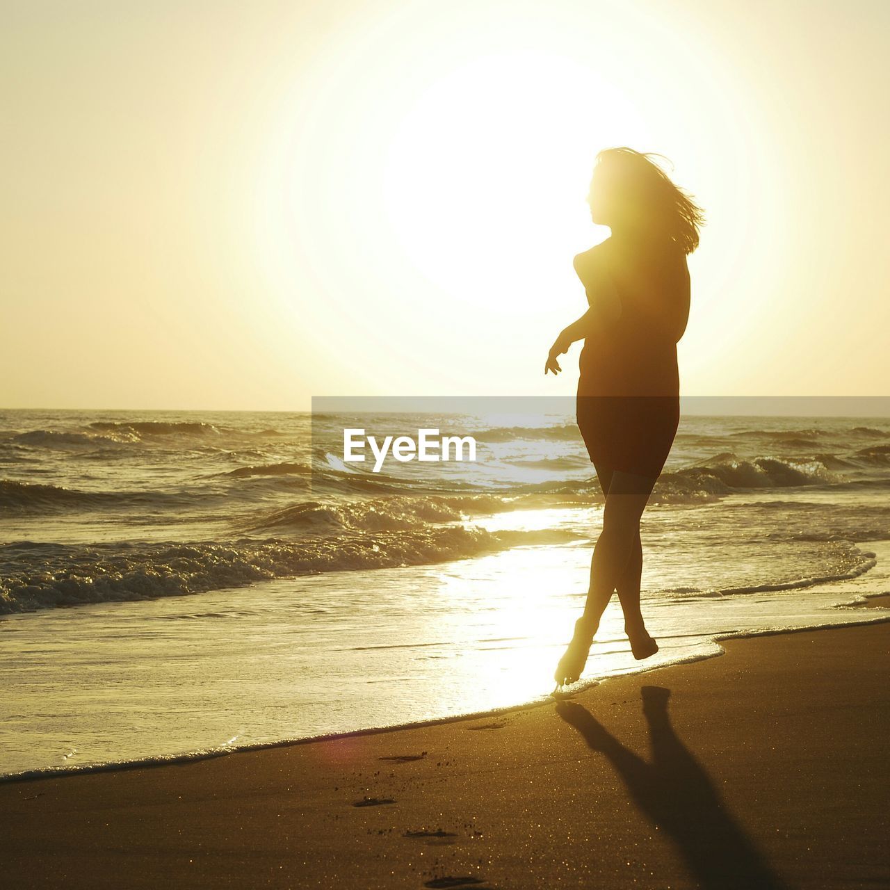 C woman running at beach during sunset